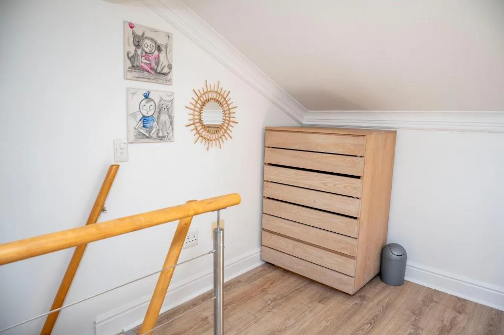 Stairway landing with wooden drawer chest and decorative wall art