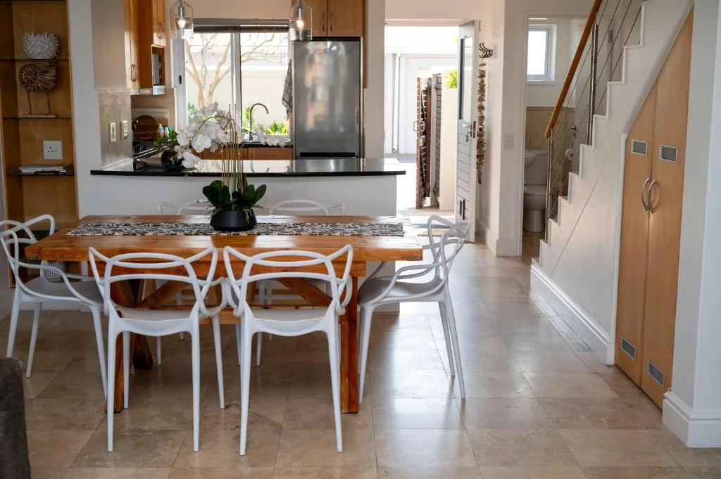 Modern dining room with wooden table and white chairs, open-plan kitchen view