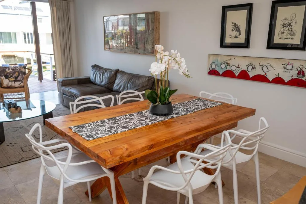 Wooden dining table with white chairs and white orchid centerpiece