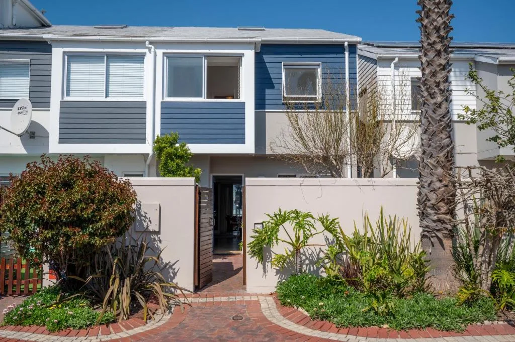 Blue and white modern townhouse with brick garden entrance and palm tree