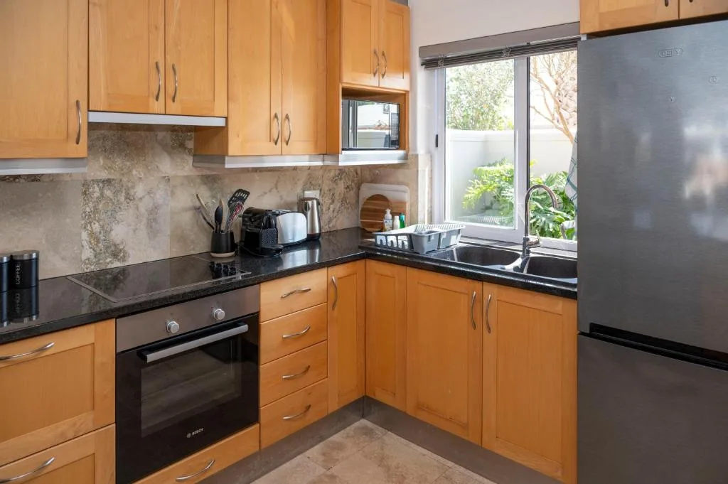 Modern kitchen with wooden cabinets, black countertops, and stainless steel appliances