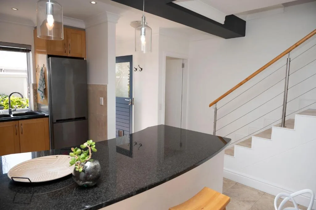 Modern kitchen with dark countertop, wood cabinets, and stainless steel appliances