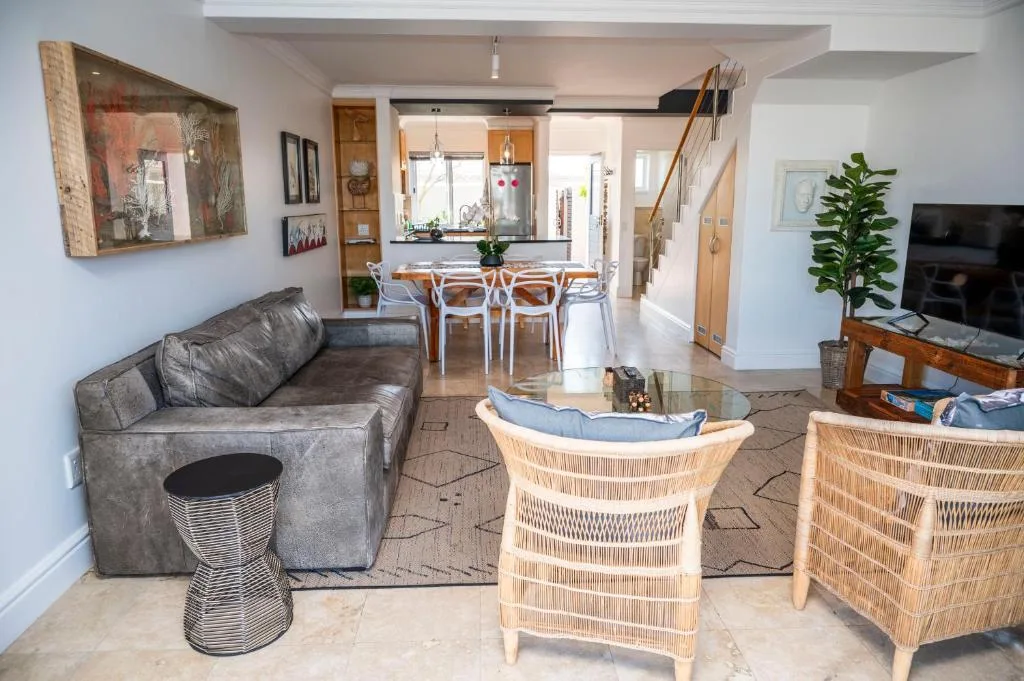 Open-plan living room with gray sofa, rattan chairs, and TV entertainment area