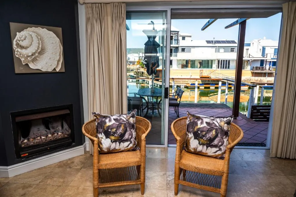 Waterfront lounge with wicker chairs, fireplace, and harbor views through glass doors