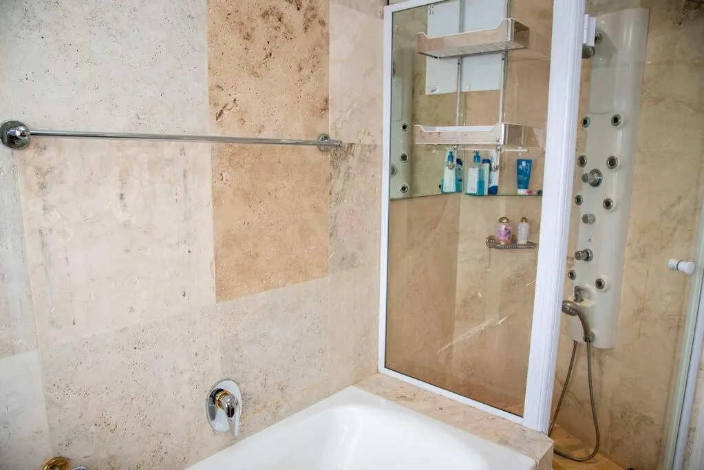 Modern bathroom with travertine tiling, glass shower enclosure, and chrome fixtures