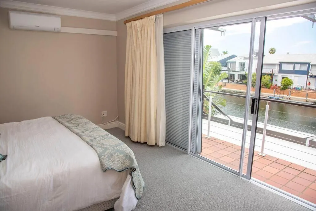 Bedroom with waterfront views through sliding glass doors and deck access