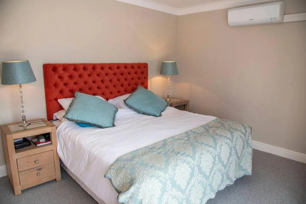 Modern bedroom with red upholstered headboard and teal accent pillows
