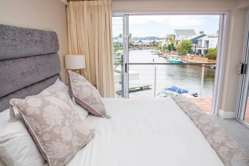 Waterfront bedroom with bed overlooking lagoon and boats