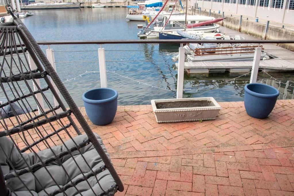 Waterfront patio with blue planters overlooking moored sailboats and harbor