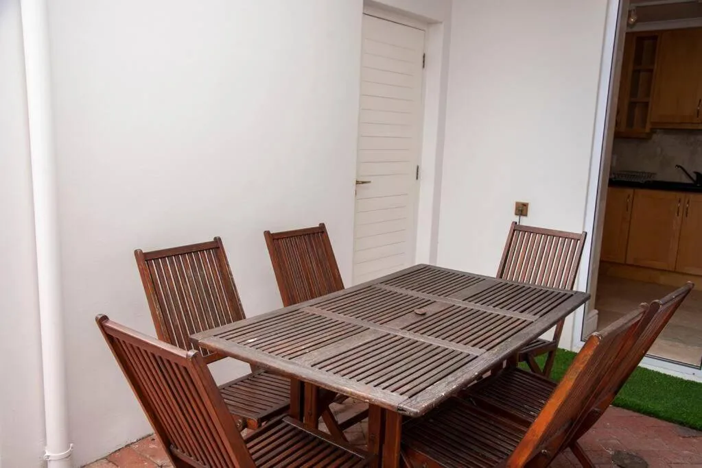 Wooden outdoor dining table with four chairs on covered patio area