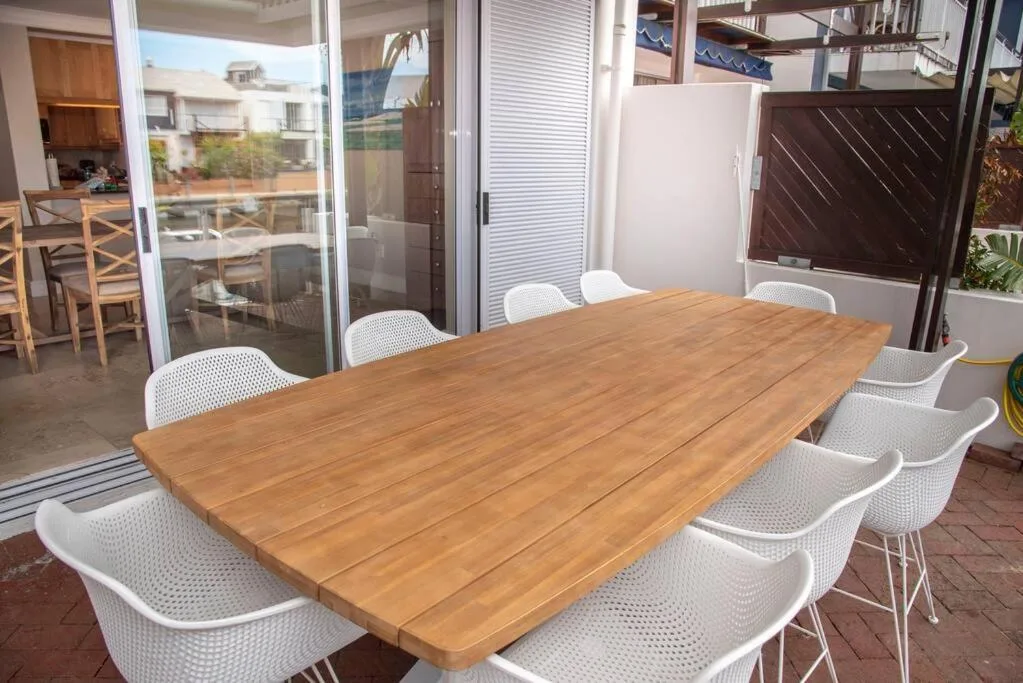 Wooden dining table with white chairs on covered patio area