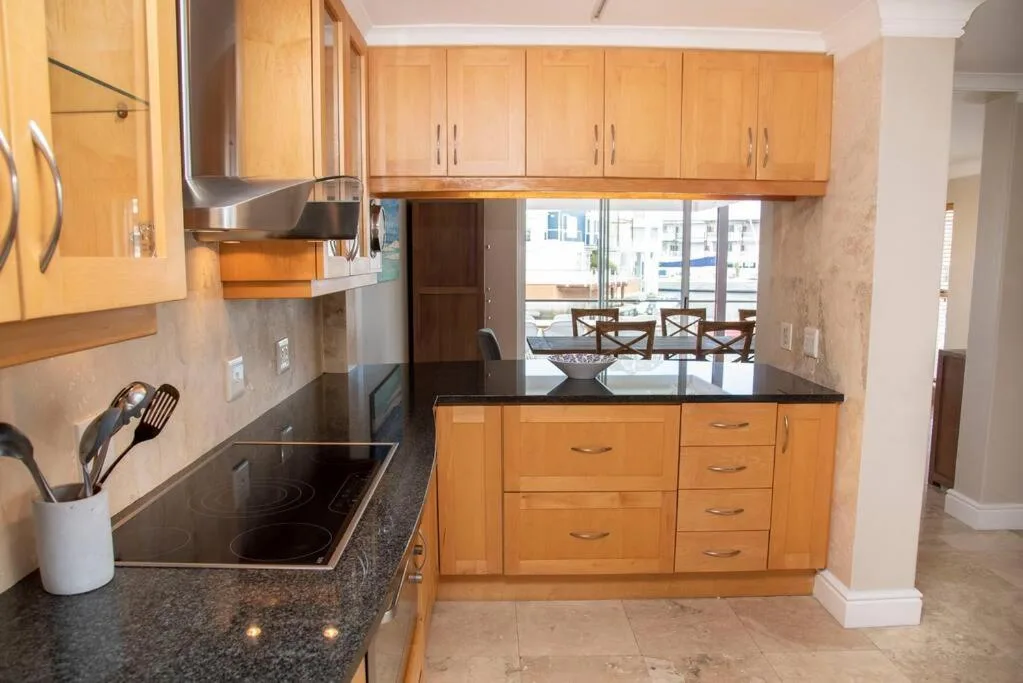 Modern kitchen with wooden cabinetry, black granite countertop, stainless steel appliances