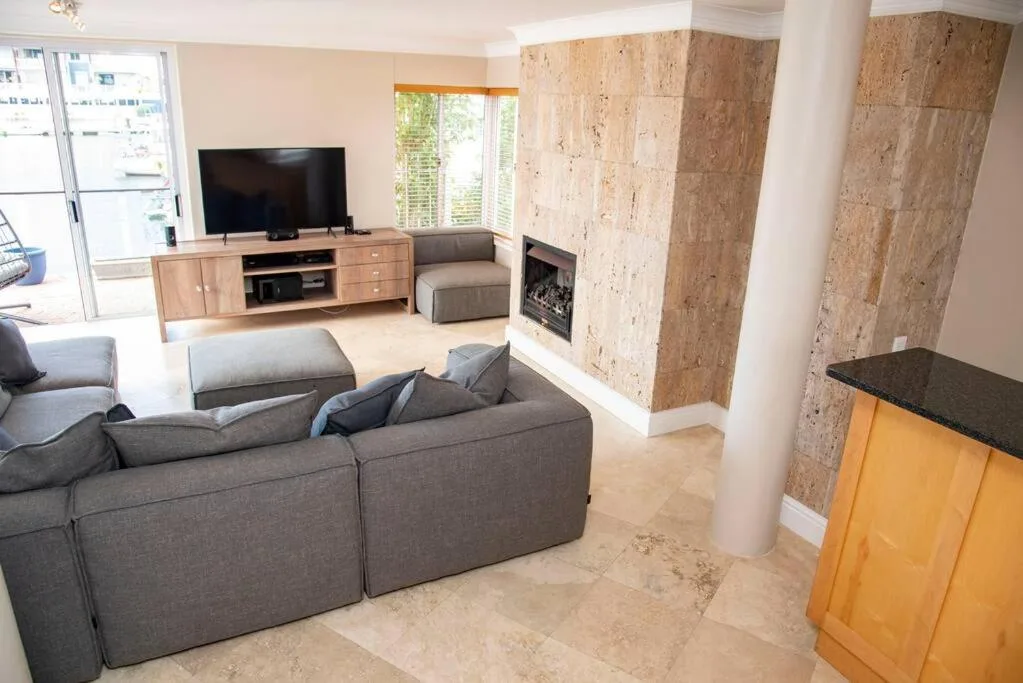 Modern living room with gray sectional sofa, flat-screen TV, and fireplace