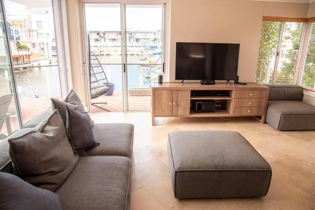 Spacious lounge with gray sofas, TV, waterfront views through glass doors