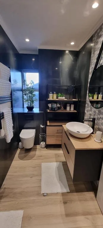 Modern bathroom with dark walls, wooden vanity, and vessel sink