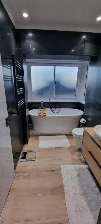 Modern bathroom with soaking tub, vanity, and window overlooking water