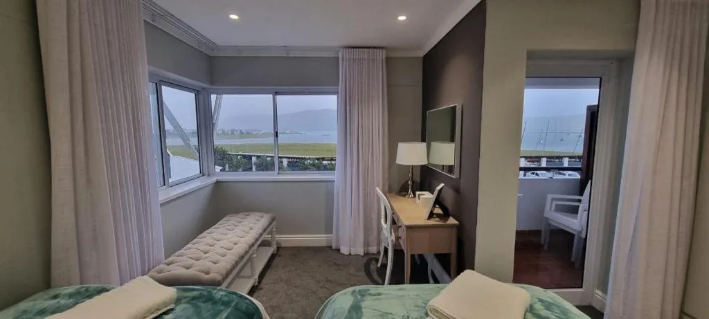 Modern bedroom with water view, bench seating, and contemporary furnishings overlooking canal