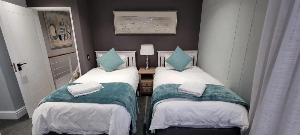 Twin beds with turquoise accents in modern bedroom with dark accent wall