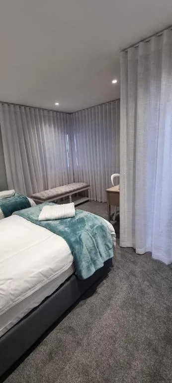 Modern bedroom with queen bed, teal bedding, and floor-to-ceiling curtains
