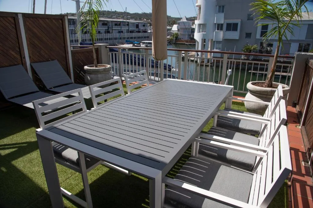 Spacious waterfront deck with dining table and lounge chairs overlooking canal