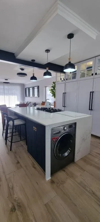 Modern kitchen with island, black pendant lights, and integrated washing machine