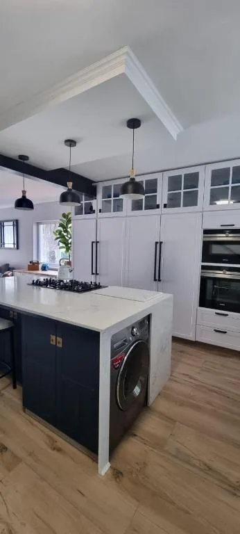 Modern kitchen with island, gas cooktop, black pendant lights, white cabinetry
