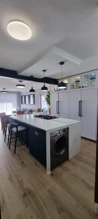 Modern kitchen with dark island, white countertops, and pendant lighting