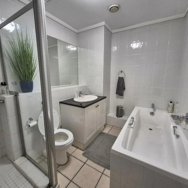 Modern bathroom with shower, toilet, vanity sink, and bathtub in bright white tiling