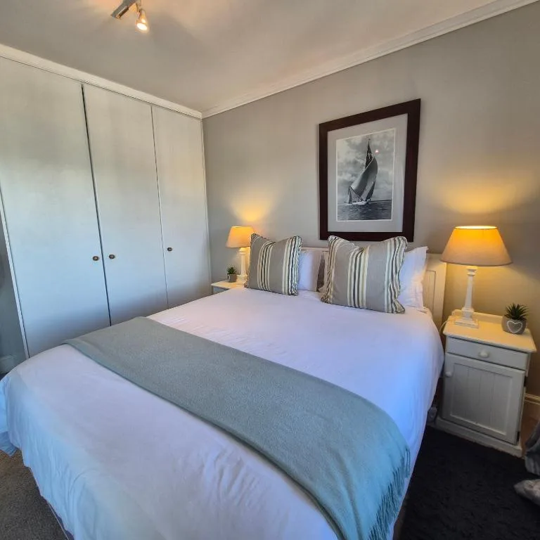 Bright bedroom with queen bed, striped pillows, built-in wardrobes, and warm lighting