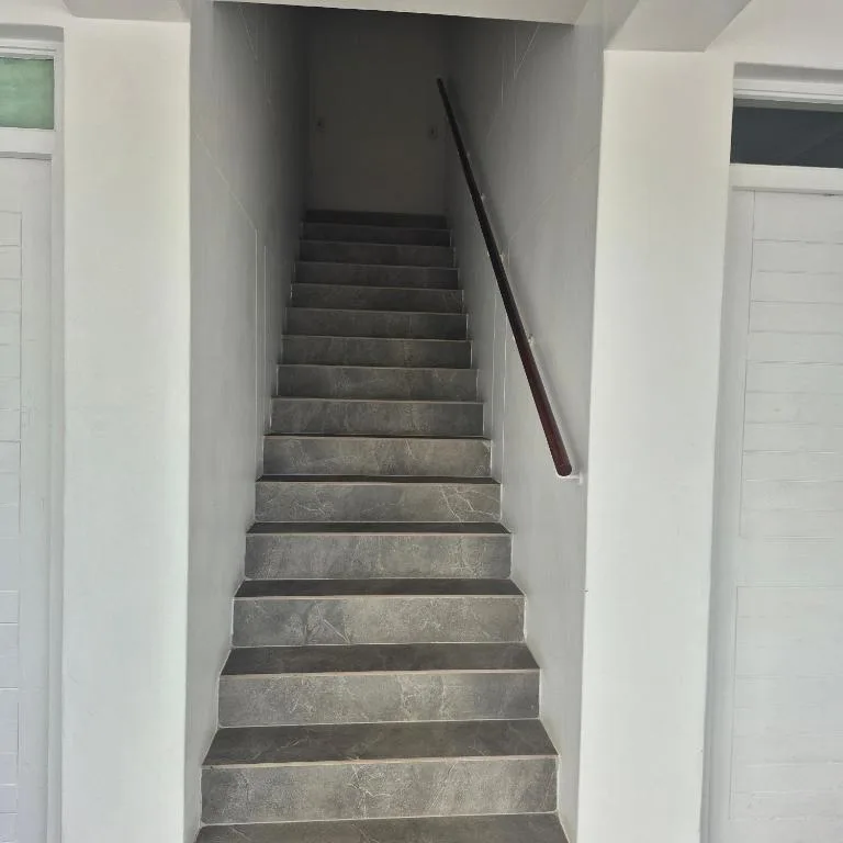 Indoor staircase with grey tile steps and wooden handrail