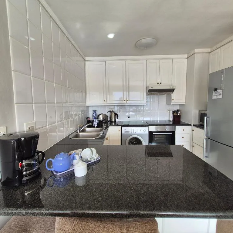 Modern kitchen with white cabinets, dark granite countertop, and stainless steel appliances