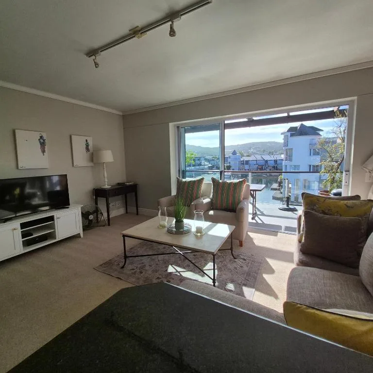 Bright living room with sofas, TV, and mountain views through large windows