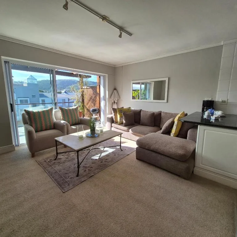 Bright lounge with gray sofa, armchair, coffee table, and waterfront views through glass doors