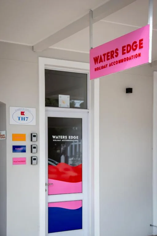 Waters Edge Holiday Accommodation signage and entrance door with colorful branding