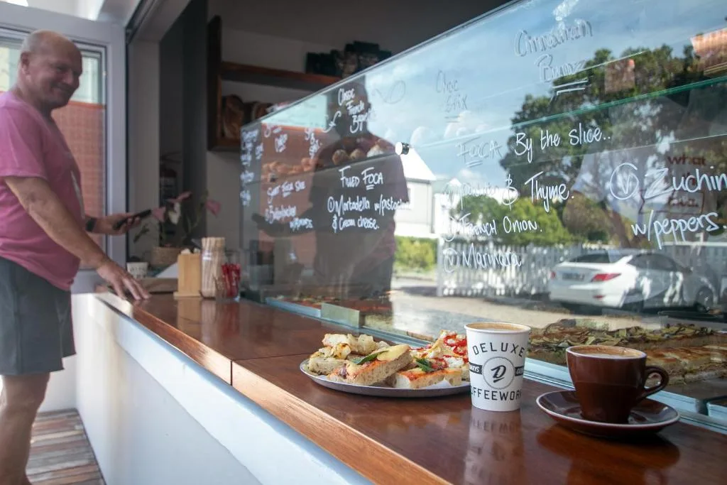 Coffee shop counter with pastries, beverages, and handwritten menu board