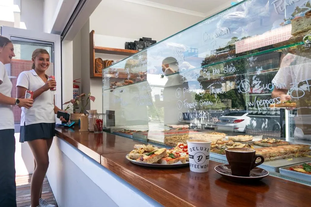 Coffee shop counter with pastries, beverages, and menu board display