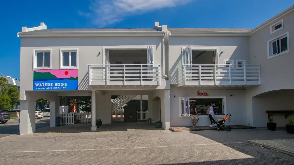 Modern white apartment building with colorful Waters Edge sign and multiple balconies