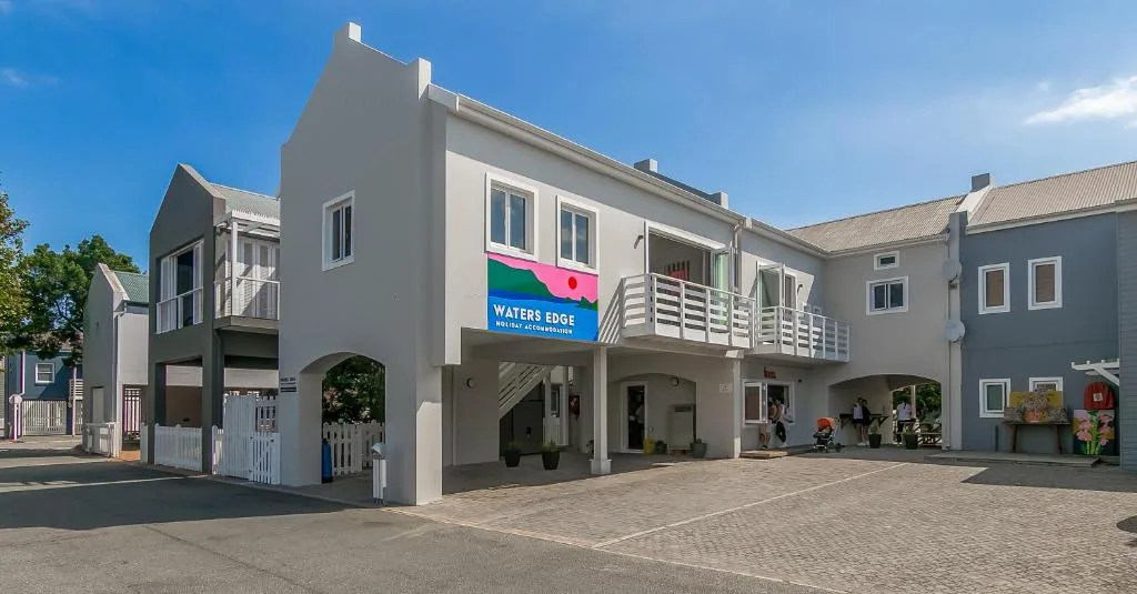 Modern gray apartment building with white railings and Waters Edge signage