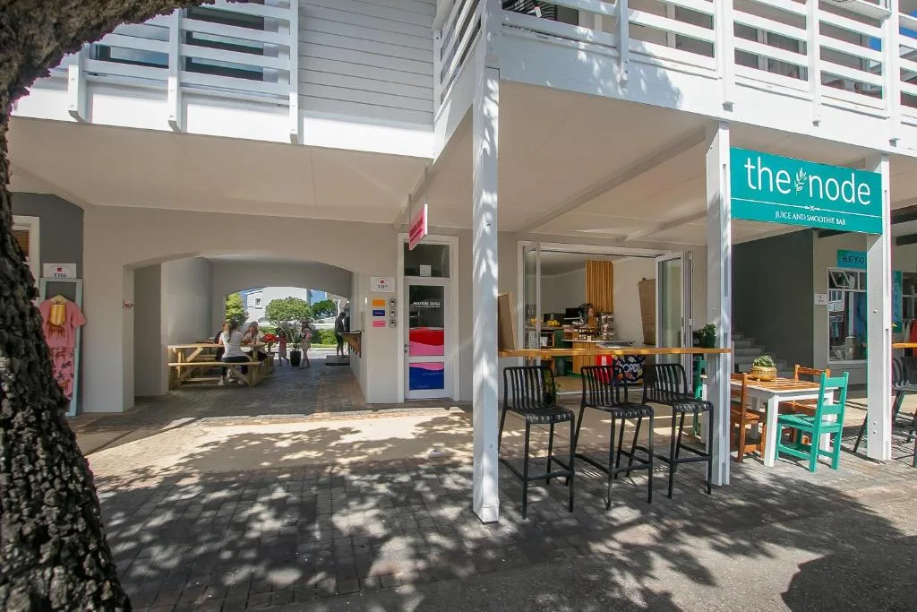 Modern building exterior with covered entrance and adjacent juice bar storefront