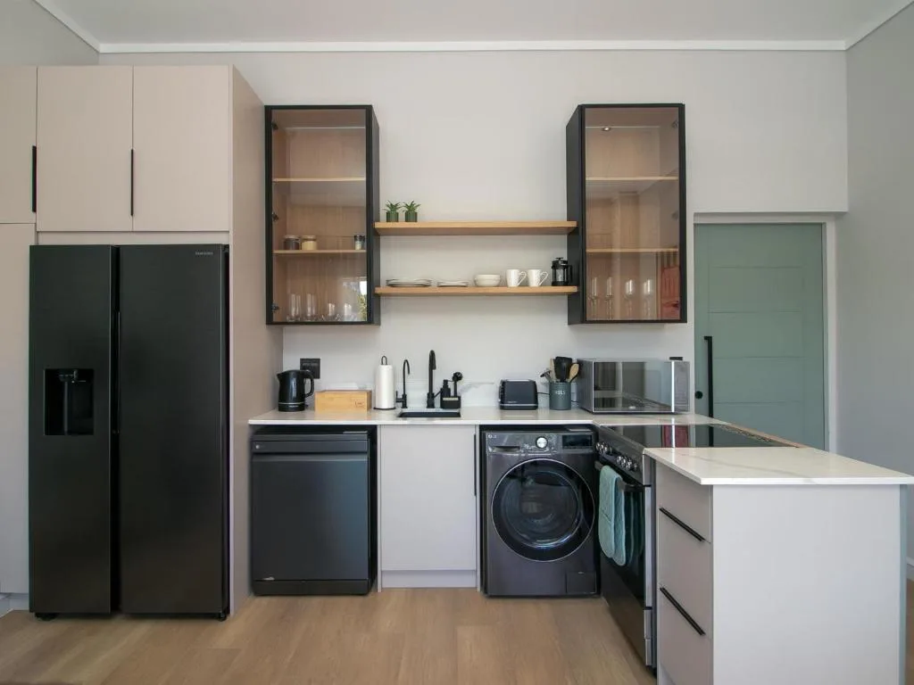 Modern kitchen with black appliances, white cabinetry, and glass-front storage units