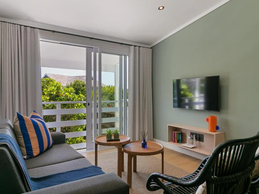 Modern living room with sage walls, sofas, TV, and garden view doors