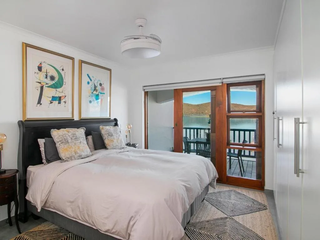 Bright bedroom with black bed frame, water views through wooden doors