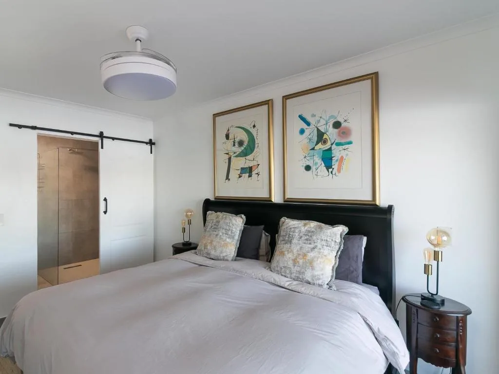 Modern bedroom with black headboard bed, white bedding, and contemporary wall art