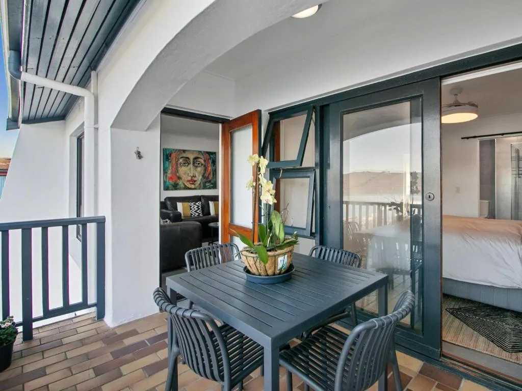 Covered outdoor dining area with table, chairs, and ocean view doors