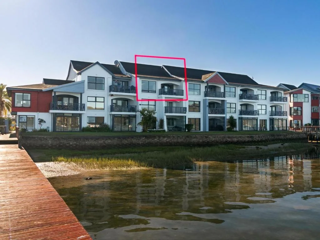Waterfront apartment building with multiple balconies overlooking lagoon