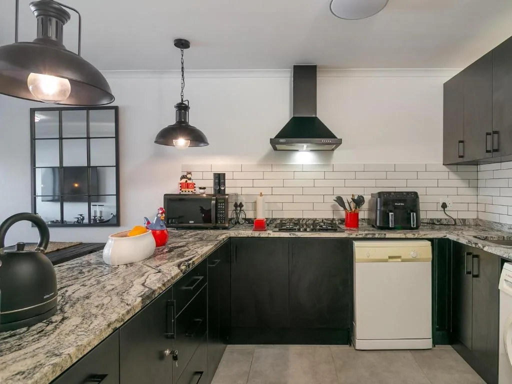 Modern kitchen with dark cabinetry, granite countertops, and stainless steel appliances
