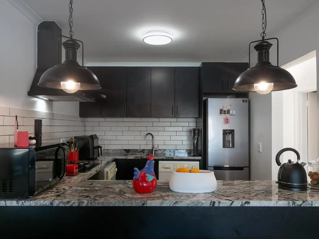 Modern kitchen with black cabinets, granite countertop, stainless steel appliances