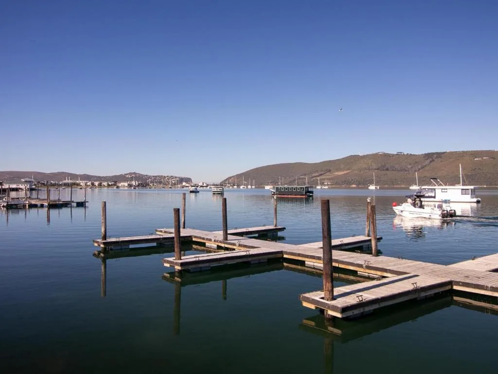 Calm lagoon waters with wooden jetties and moored boats under blue sky