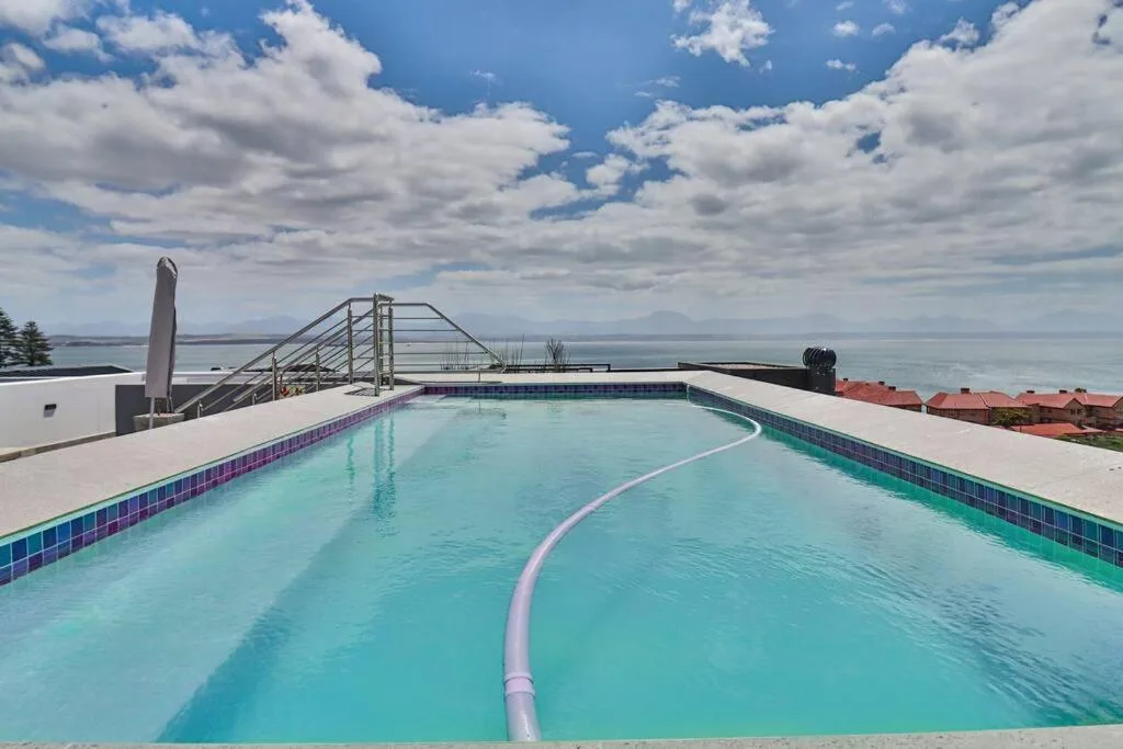 Sparkling swimming pool overlooking ocean with coastal mountains in distance
