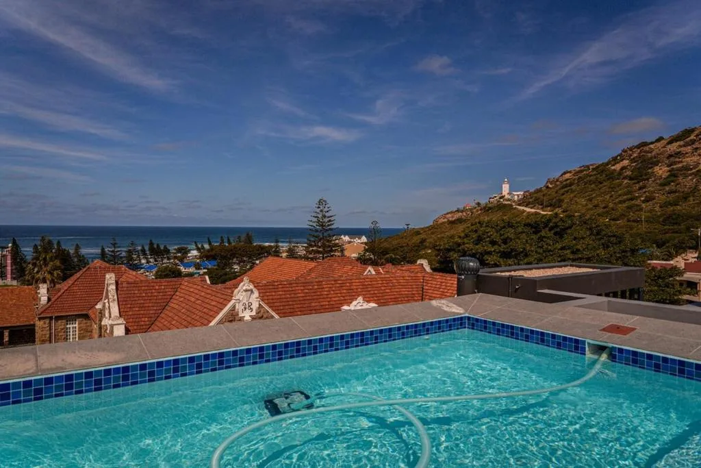 Swimming pool overlooking Mossel Bay coast with lighthouse and red-roofed buildings